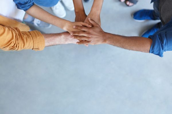 Friendship, partnership, togetherness, collaboration concept. Group of international friends stacking their hands expressing their friendship, agreement and support. People piling their hands
